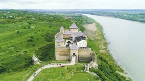 Aerial view of medieval castle on river coast. Camera moves down.
