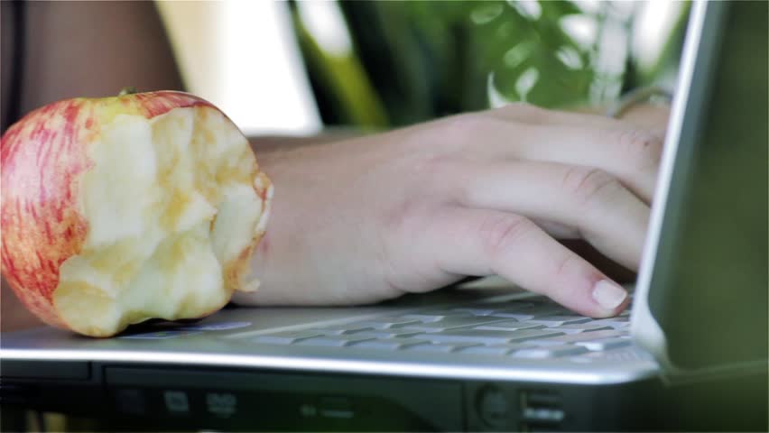 Young Woman Enjoying an Apple and Working on a Laptop in the Open Air - Close Up