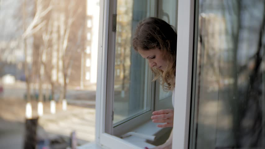 attractive girl washes windows at home. To clean up the house. 4k