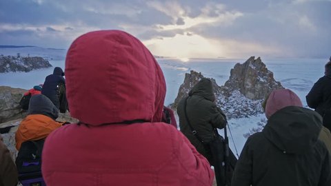 RUSSIA, OLKHON - MARCH 1, 2018: Large group of tourist watching and taking photos of famous sunset view in Lake Baikal. 스톡 비디오