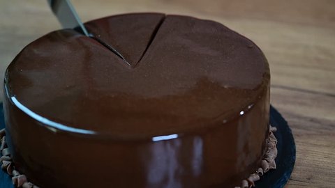 Glazing chocolate mousse cake, close-up. Cut a piece of chocolate cake with a knife.