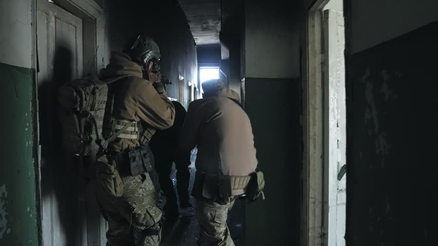 Soldiers in camouflage with combat weapons sneak along the corridors of the old building, the military concept 4k