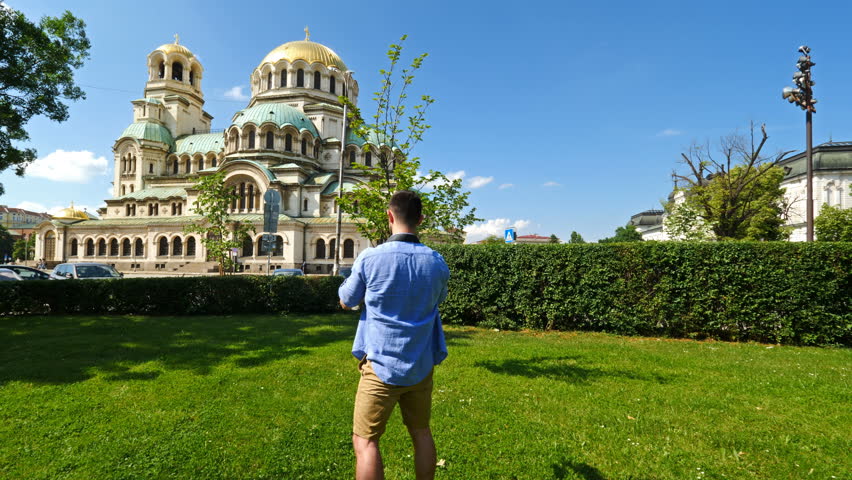 Young caucasian man takes pictures to Alexander Nevsky cathedral in Sofia, Bulgaria. Solo traveler concept. Cinematic movement.