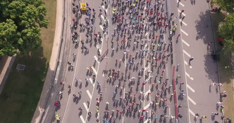 Aerial view from drone on crowd of people who is starting their run on marathon event. Funny shadows on asphalt.