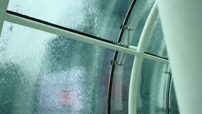 Singapore - May 2018:  Rain water pouring on window with column in foreground. Shallow depth of field. 4K resolution
