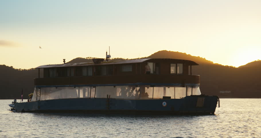 Man on wooden boat docked in the water at sunset