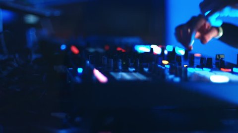 A DJ behind the console, on stage, mixing tracks in atmospheric dance party strobing and flashing lights. Video de stock