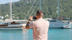 Young man make panoramic photo or video with smartphone near sea beach
