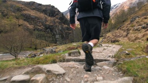 Young Hiker with backpack bag running along Scottish Highlands trail path.  Traveller exploring rural Scotland Mountain area UK 