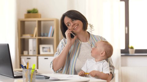multi-tasking, freelance and motherhood concept - working mother with baby boy at home office calling on smartphone