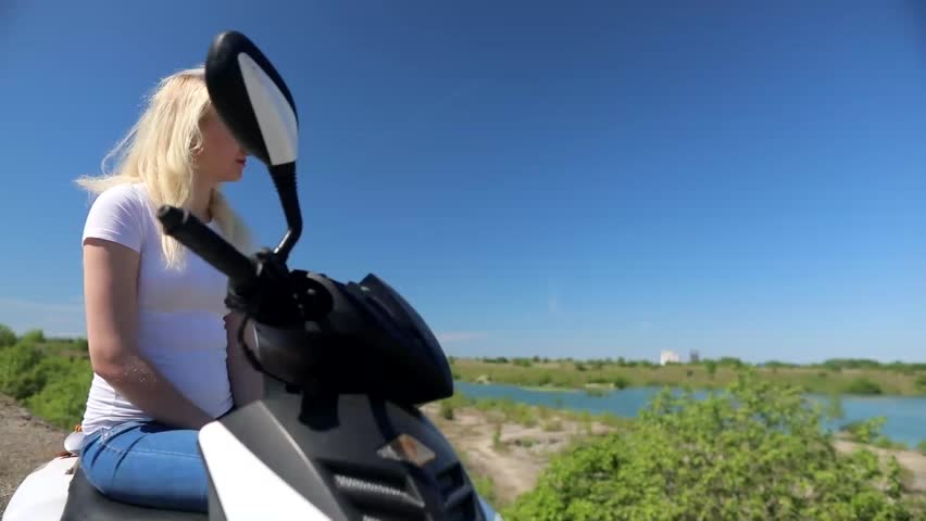 young couple sitting back in the camera, looking at the lake in the distance, hugging and kissing.