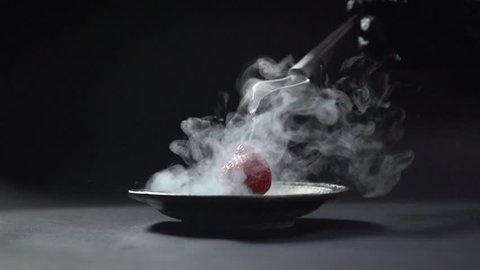 The liquid flows from the curved spoon to the berry.