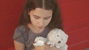 Pretty baby girl kid eating slow motion video nursing bottle licking lifestyle big ice cream in waffle cone with raspberry happy laughing on red background. the girl teenager and ice cream concept