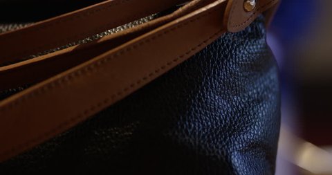Leather purse with woman talking out of focus in background