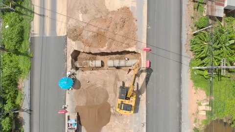 Water pipe excavator job by backhoe and workers near road construction site
