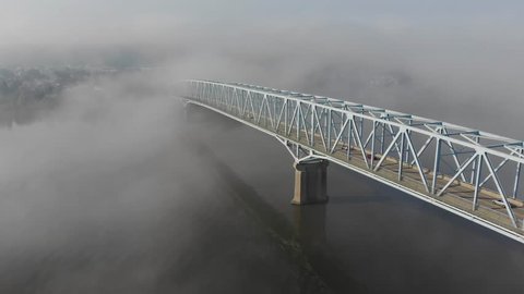 A high angle slow forward aerial establishing shot of a bridge over the Ohio River on a foggy morning. Pittsburgh suburbs.  	