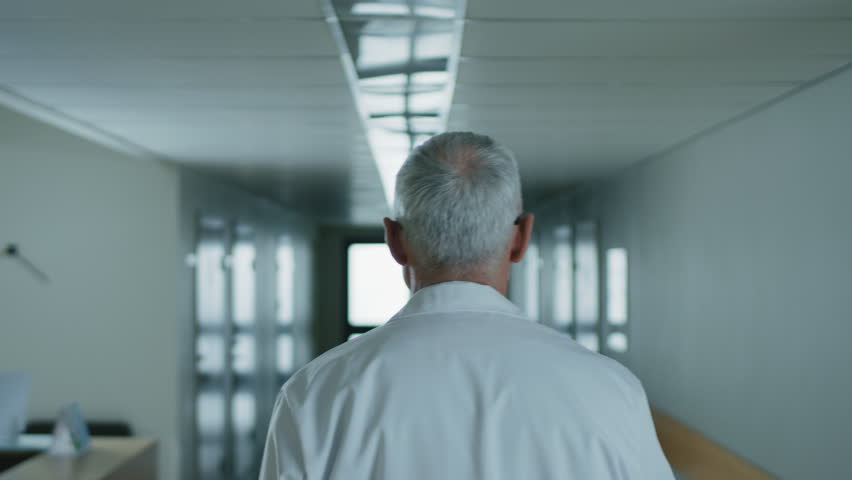 Following Shot of the Professional Male Doctor Walking Through Hospital Hallway. Portrait Footage. Shot on RED EPIC-W 8K Helium Cinema Camera. Royalty-Free Stock Footage #1011621764