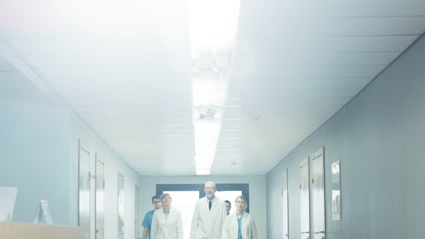 Team of Doctors, Nurses and Assistants Walking through the Hallway of the Hospital. Professional Medical Personnel Working, Saving Lives. Slow Motion. Shot on RED EPIC-W 8K Helium Cinema Camera. Royalty-Free Stock Footage #1011621785