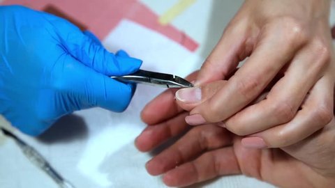 The manicurist bites the cuticle with nippers