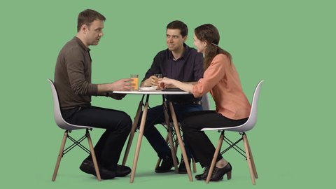 Two men and a girl sitting at a table in a cafe and talk
