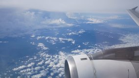 View of the sky above cloud level from the cabin window of airplane (plane) flying in the sky in clear day with some cloud (See plane engine and wing)-4K UHD video movie footage short