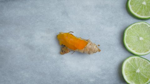 Woman slices fresh turmeric root on a marble cutting board in 4k. Top down view of the fresh bright orange root used to make golden milk which is full of health benefits for juicing and paleo diets