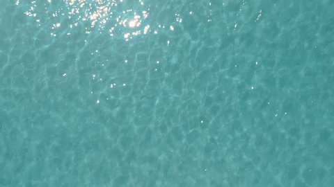 Sunny day top view of crystal clear water, looped background, natural texture