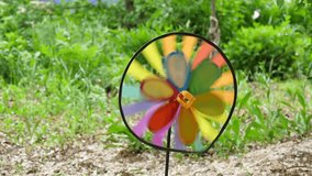 One colorful circle of a propeller spinning in the wind against a background of green grass