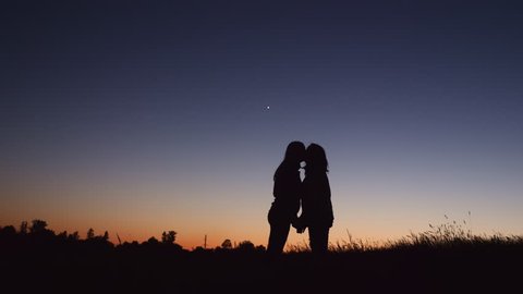 Silhouette lesbian couple kissing at sunset time late evening