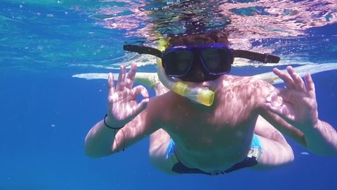 Boy dive in Red sea near coral reef, showing ok symbol, underwater shoot