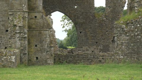 Cashel, Ireland - May, 2016: Zoom in view of tree branches seen through an arched gate of the Hore Abbey monastery