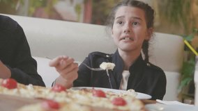girl teen eats pizza in cafe slow motion video. children eat pizza a delicious pizza. company of people lifestyle friends eating in a cafe. kids eating pizza concept