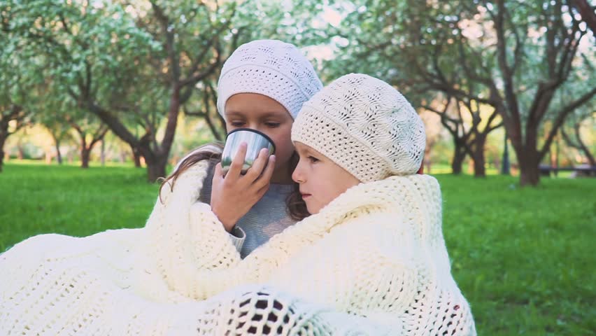 Two girls are drinking tea in the park. Are heated. Close-up.