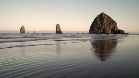 Haystack Rock and the Needles, Cannon Beach. Sunrise at Haystack Rock and the Needles in Cannon Beach, Oregon as the surf washes up onto the beach. United States.

