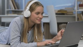 Happy teenage girl in headphones listening to music and chatting with friends