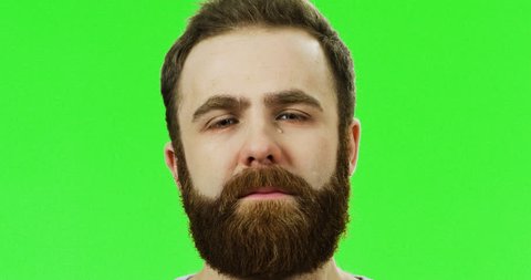Portrait of the very upset man with a beard crying as being sad on the green screen background. Chroma key. Green screen.