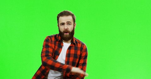 Caucasian man with a beard and in the red motley shirt dancing on the green screen background. Chroma key.