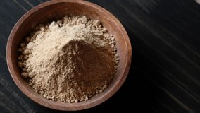 Rotating maca powder superfood in wooden bowl.