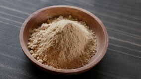 Rotating maca powder in wooden bowl.
