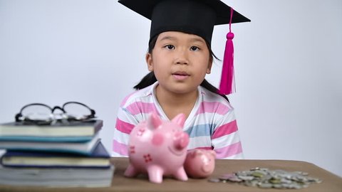 asian cute student put money to piggy bank, saving money for education