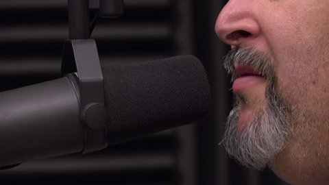Middle aged man being interviewed on radio show talking into microphone.
