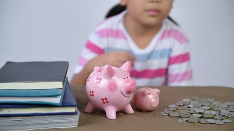 Little hand put coins to piggy bank for education, saving money concept