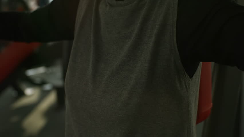 Tilt up of elderly woman with grey hair exercising on incline chess press machine in gym