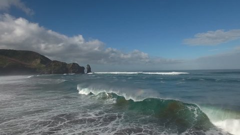 Aerial view of large surf waves breaking at Piha Beach, New Zealand