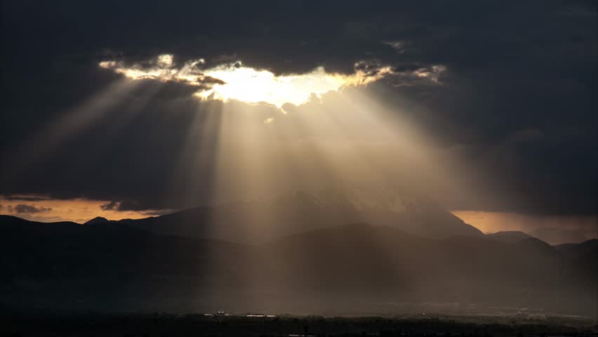 After the last rainstorm, a ray of sunshine pierces the clouds, illuminating the valley and the underlying limbs. | Shutterstock HD Video #1011700313