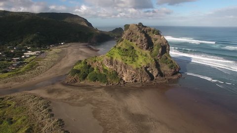 Aerial view of Lion Rock and large surf waves at Piha Beach, New Zealand