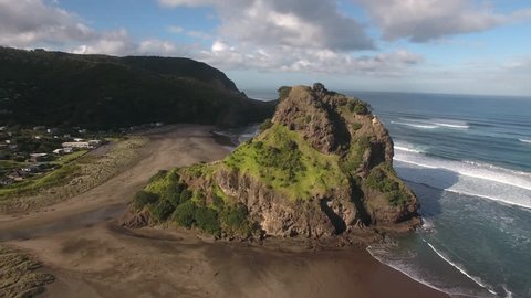 Aerial view of Lion Rock and large surf waves at Piha Beach, Auckland
