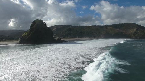 Aerial view of Lion Rock and large surf waves at Piha Beach, Auckland
