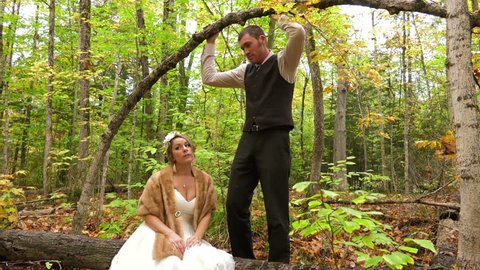 married couple pose under bent over tree for photoshoot in woods 4k