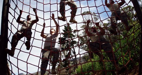 Military troops climbing a net during obstacle course at boot camp